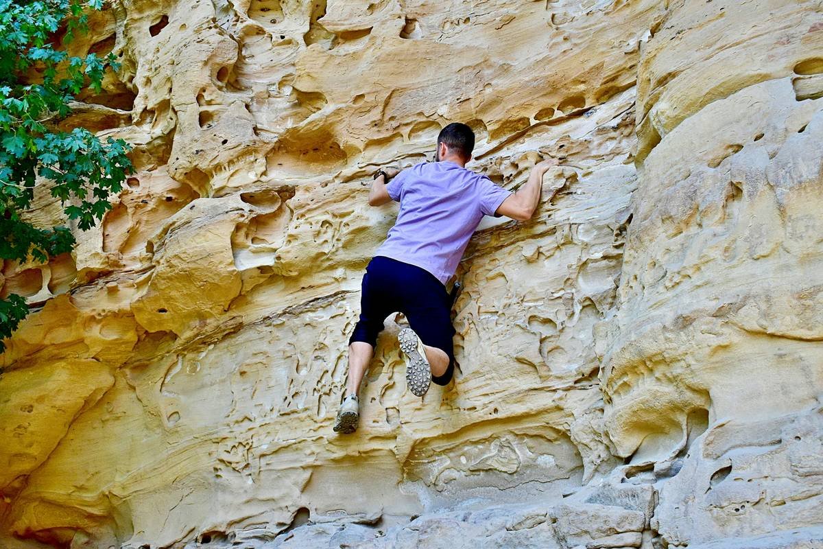 Woman performing unrestricted free climbing in breathable climbing tights on indoor bouldering wall