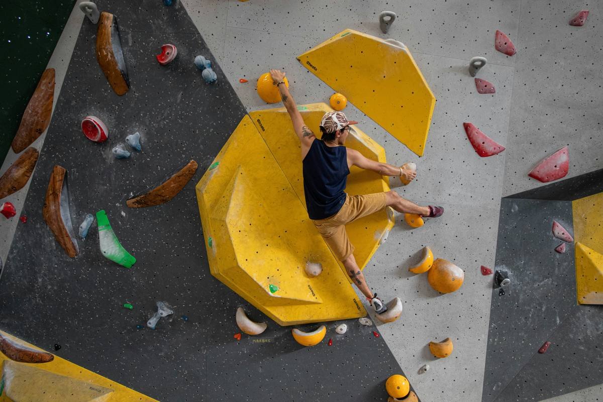 Climber performing wall climbing warm up exercises on an indoor bouldering wall