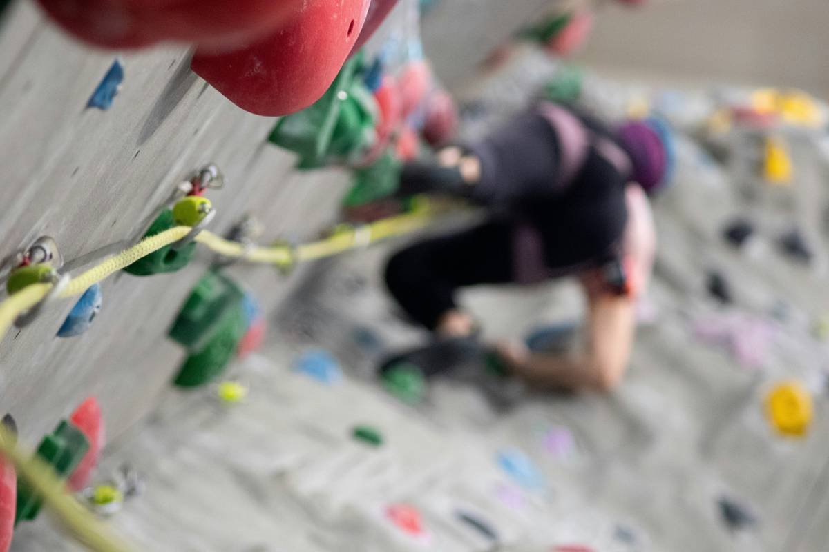 Woman wearing flexible climbing tights during outdoor bouldering session with full hip extension