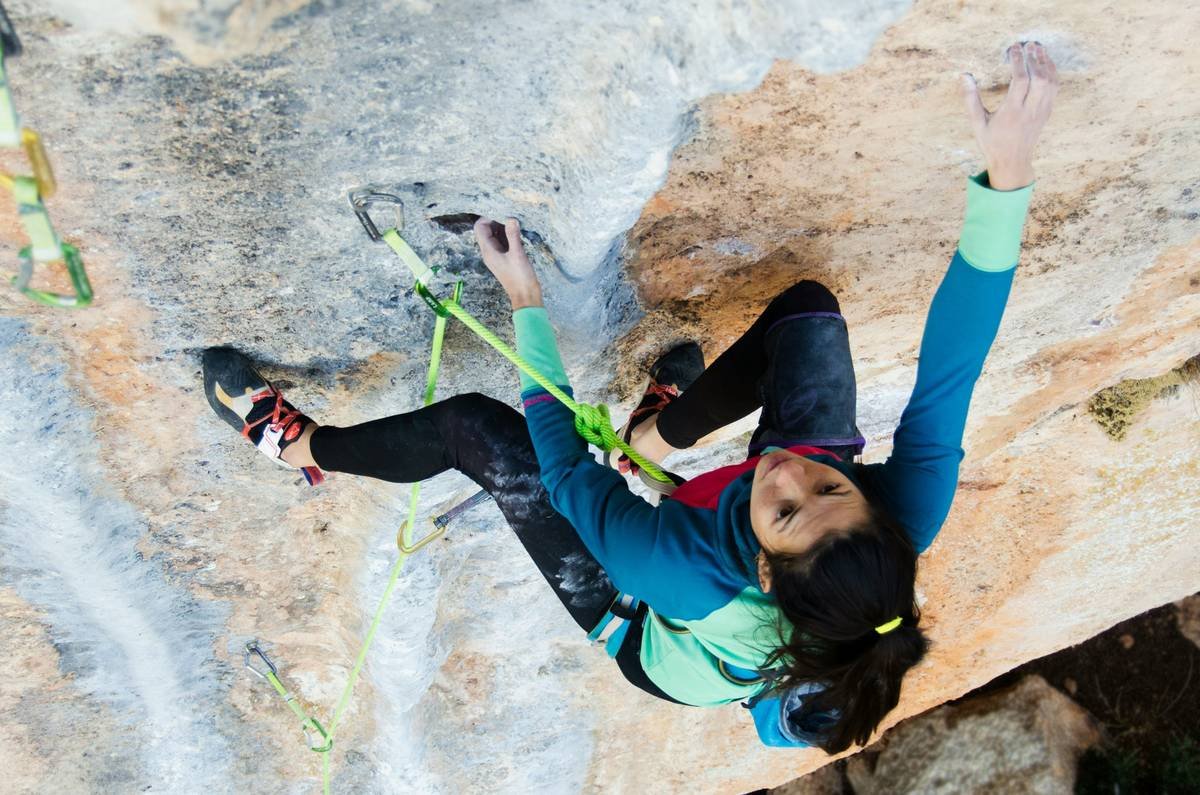 Woman performing agile free climbing on an indoor wall wearing high-performance climbing tights