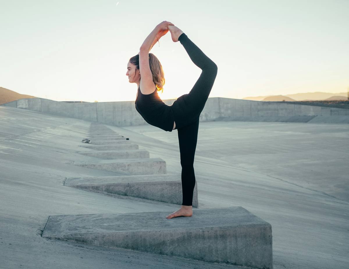 Climber in black Flex Fit tights demonstrating deep knee bend on indoor wall, showcasing climbing flexibility