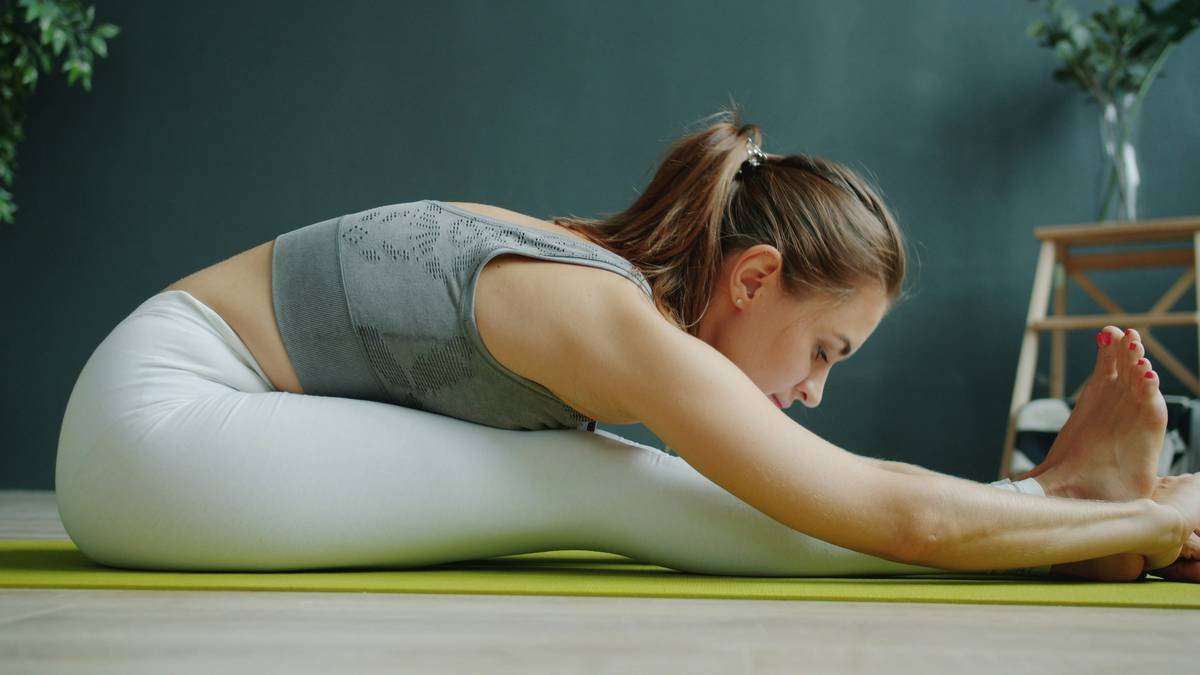 Female climber in black stretch climbing tights performing a heel hook on an overhang