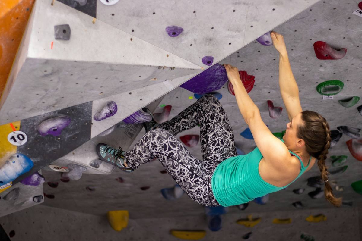 Woman bouldering indoors wearing climbing comfortable tights with moisture-wicking fabric and flat seams